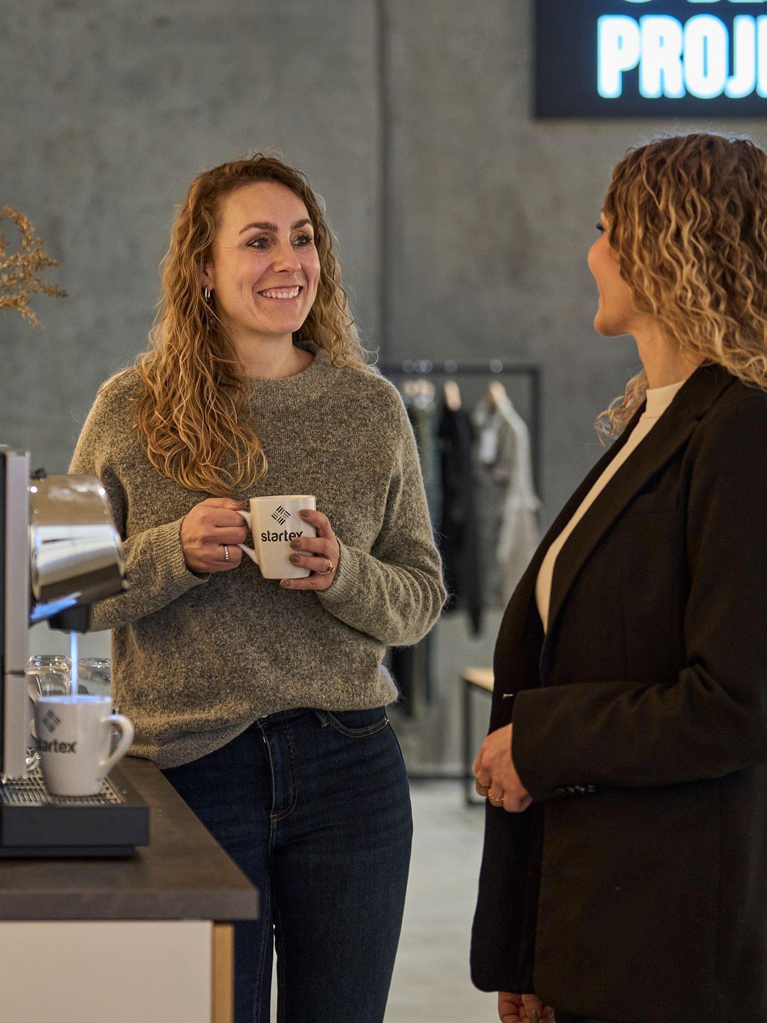 Two STARTEX colleagues talking by the coffee machine